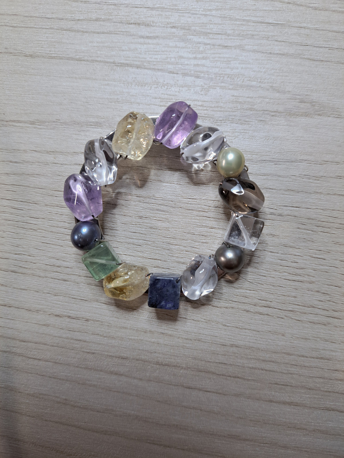 Front of multicolor circle jewelry piece with wire-wrapped translucent elements and pearl-like beads