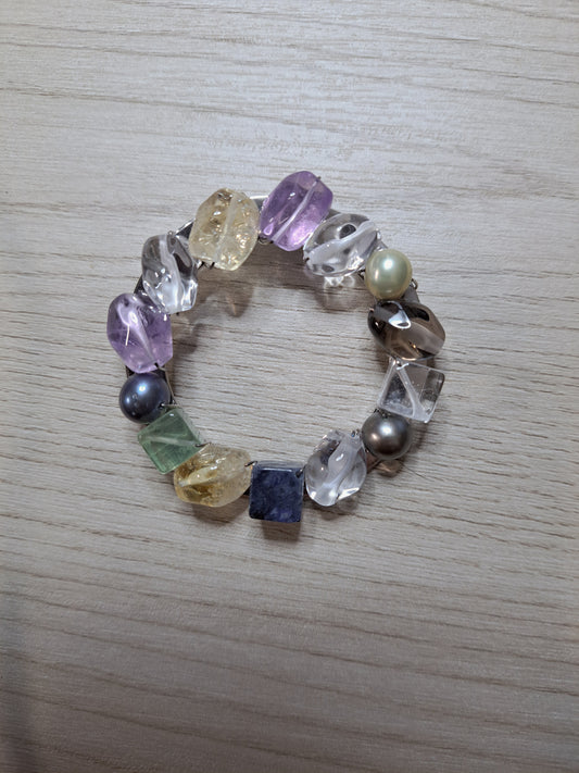 Front of multicolor circle jewelry piece with wire-wrapped translucent elements and pearl-like beads