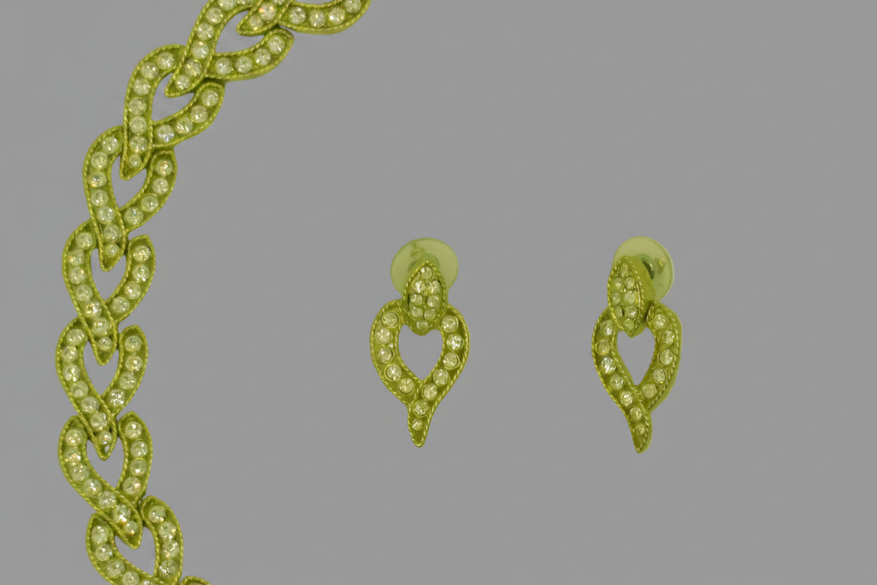 Gold chain and earrings on a light green background
