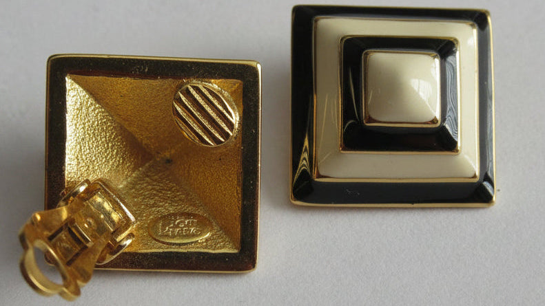 A pair of vintage square lapel pins with a gold-tone finish, one showing the textured gold back with a lobster clasp and the other showing the front with concentric black and cream enamel layers.